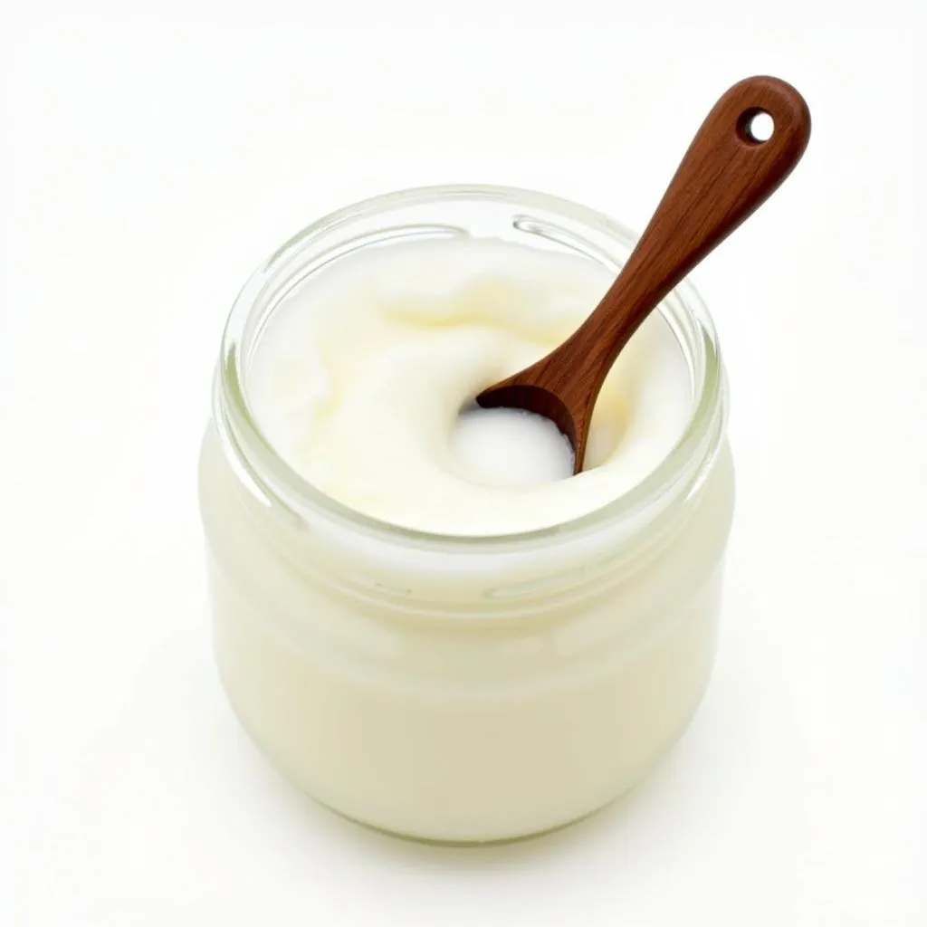 Organic coconut oil in a jar with a wooden spoon.