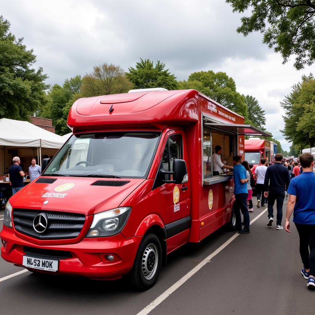 A vibrant red Mercedes food truck serving a long line of customers at a food festival.