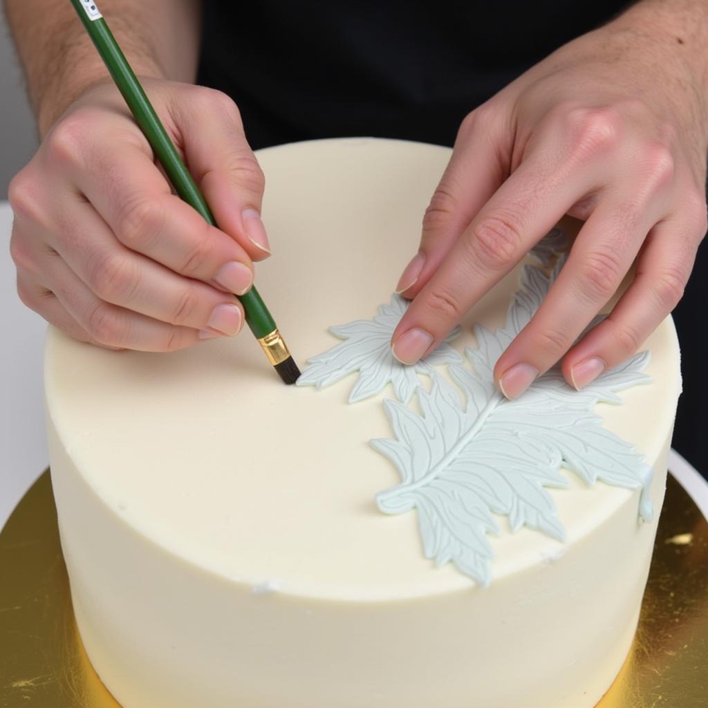 Close-up of a pastry chef using various food colour paint techniques on a fondant covered cake.