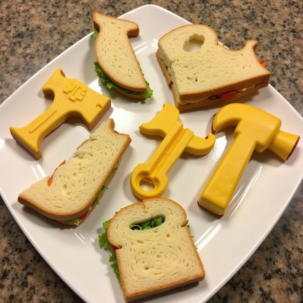 Close-up of sandwiches cut into the shapes of tools like hammers, saws, and wrenches, arranged on a platter.