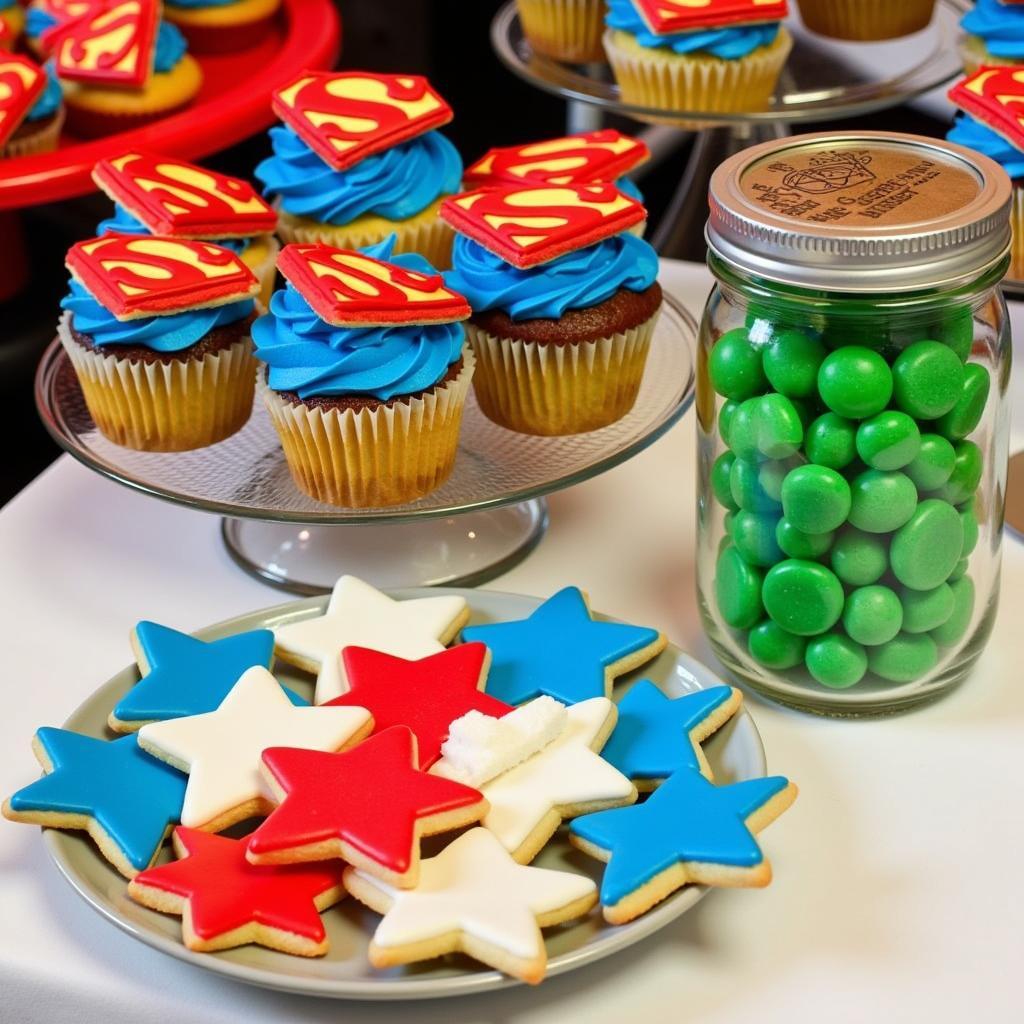 A selection of superhero themed desserts, including cupcakes, cookies, and a "Kryptonite" candy bar.